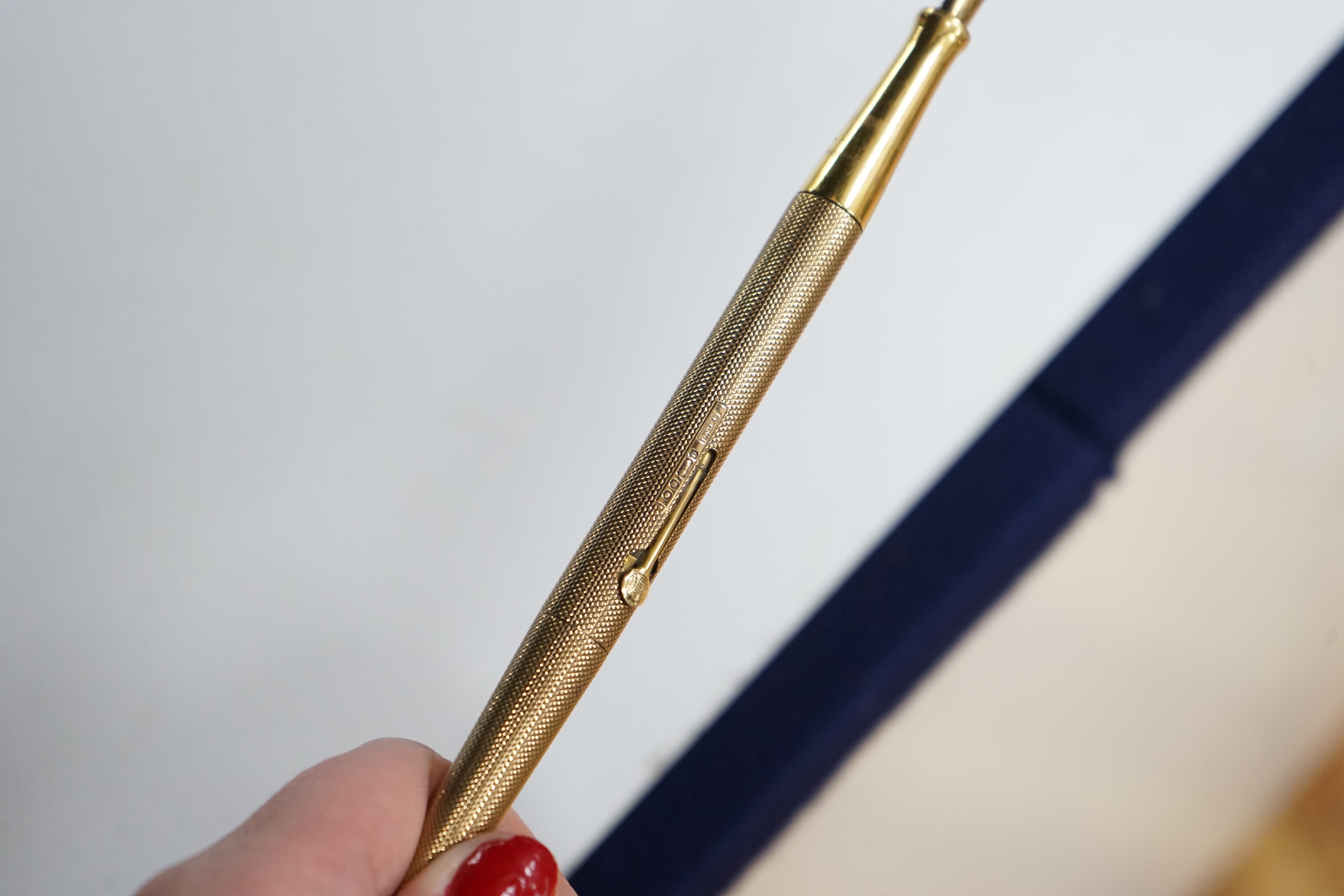 A George V engine turned 9ct. gold combination fountain pen and pencil, with holder (once attached to a stand), maker F.D.W. London, 1935, 20.4cm.
